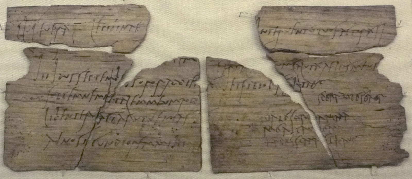 Fragments of a thin wooden Roman writing tablet bearing lines of handwritten ink.